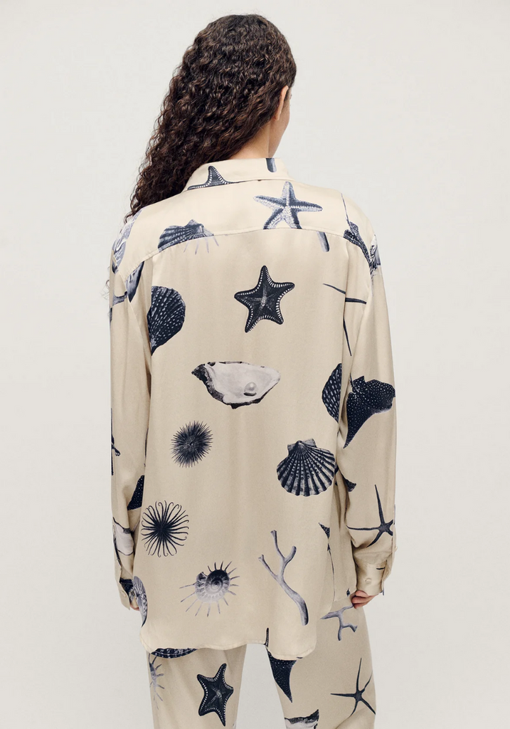 Person wearing a beige shirt with blue marine pattern on a white background