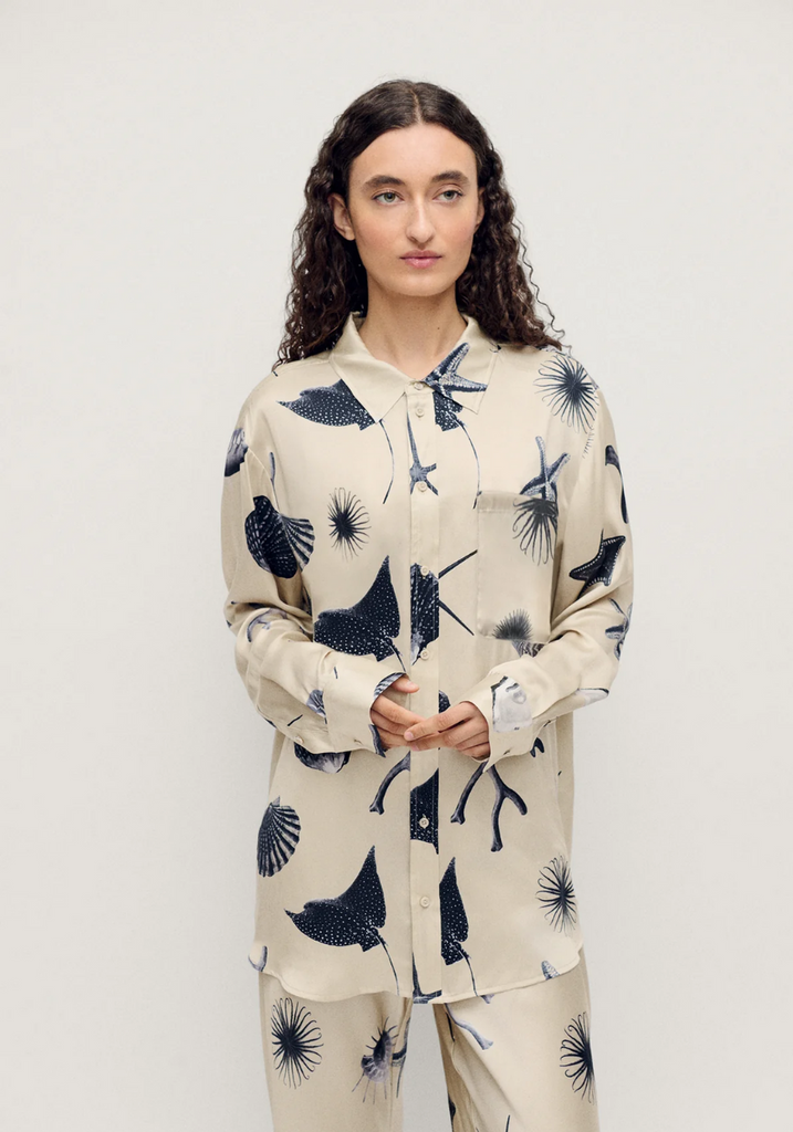 Person wearing a cream-colored pajama set with black abstract patterns on a white background
