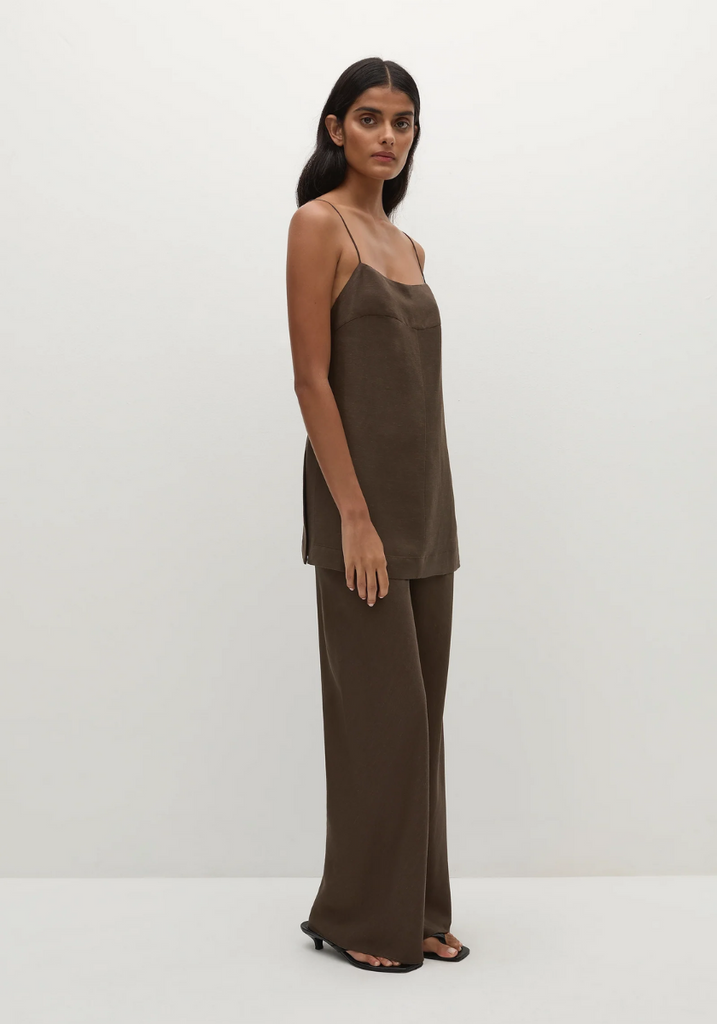 Woman wearing a brown slip top and wide-leg pants against a white background