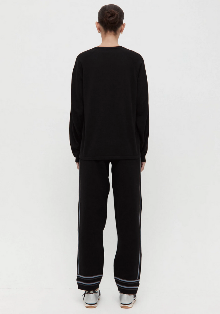 Person wearing a black outfit with striped pants on a white background