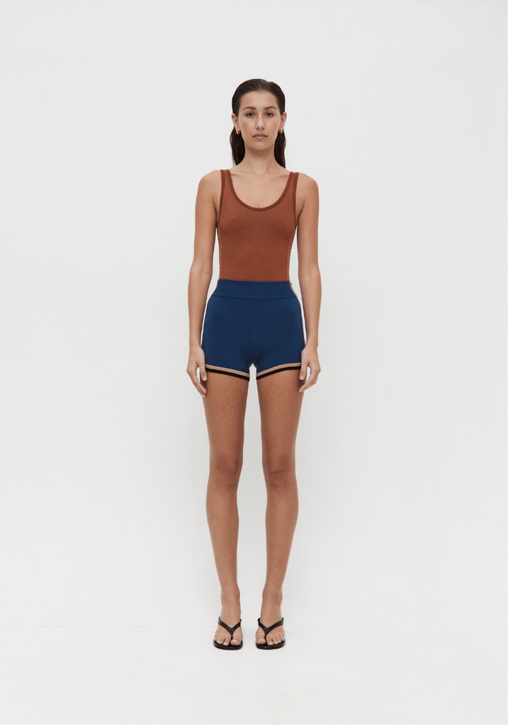 Woman wearing a brown tank top and blue shorts on a white background