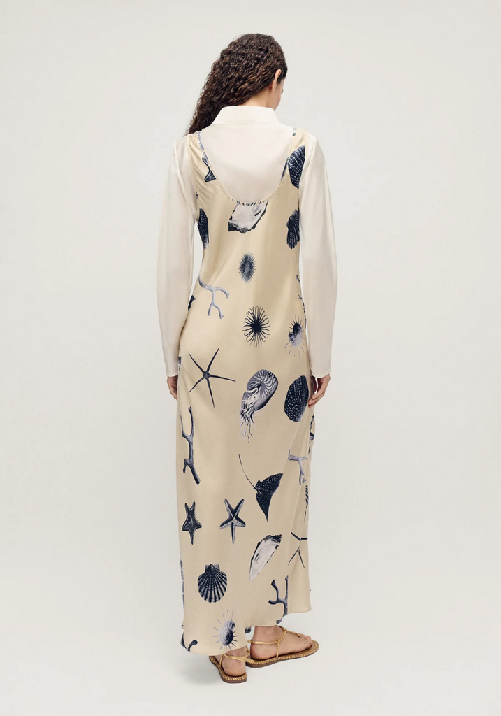 Woman wearing a long dress with marine pattern on a plain background