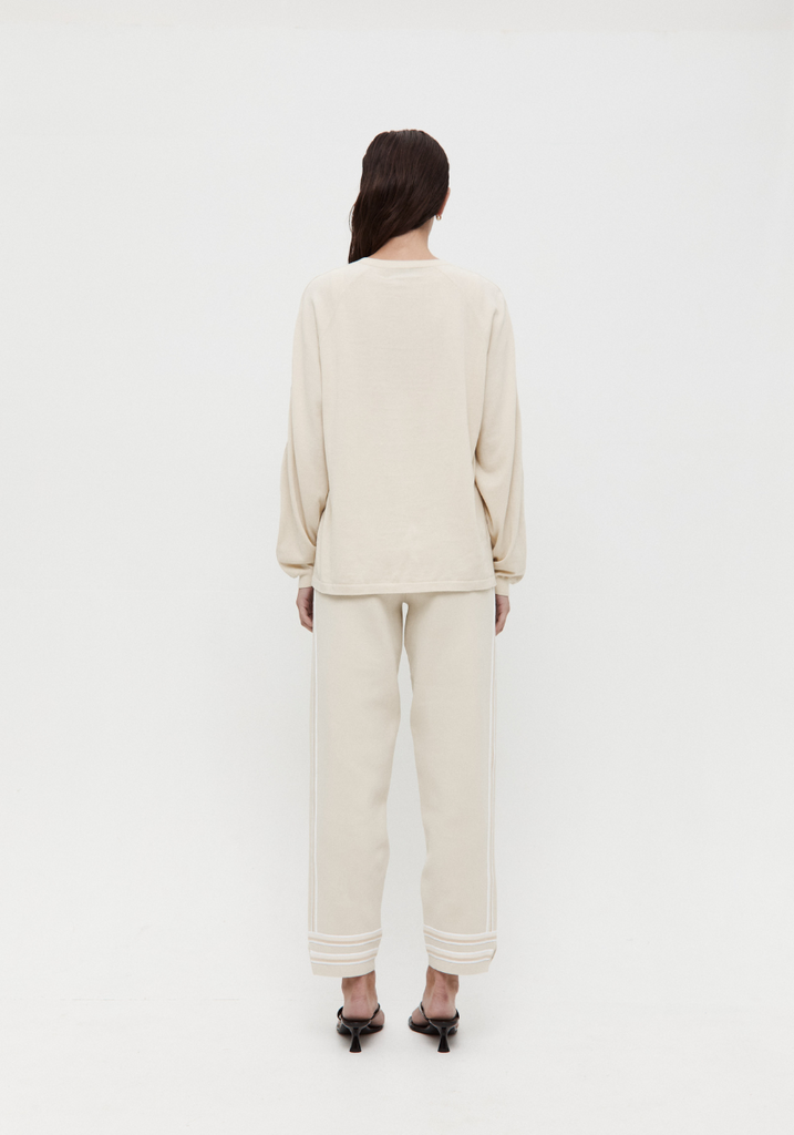 Person wearing a beige outfit standing against a white background