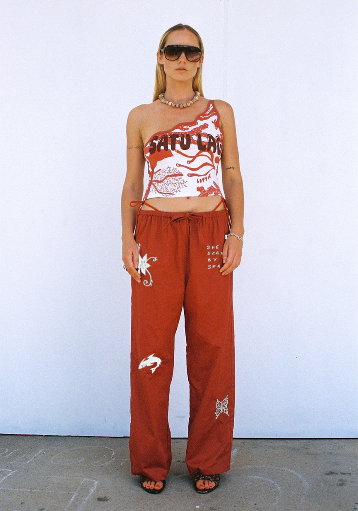 Person wearing a red tank top with graphic design and matching pants against a white background