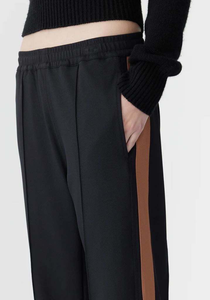Black pants with a brown stripe worn by a person on a white background