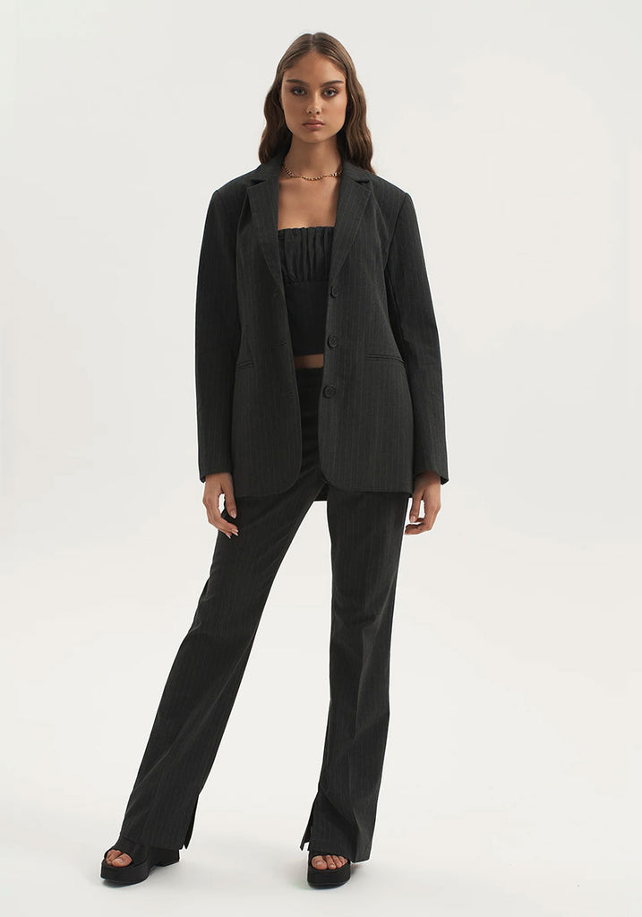 Woman wearing 3 piece matching set pinstripe pants and jacket